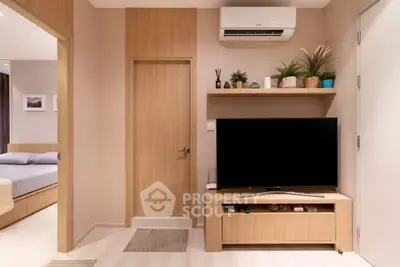 Modern living room with sleek TV setup and stylish decor, adjacent to cozy bedroom.