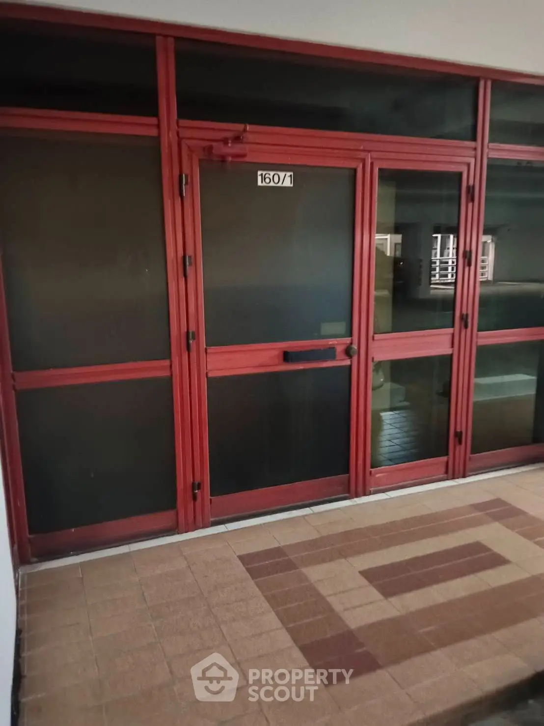 Red-framed glass entrance with tiled floor, ideal for commercial real estate.