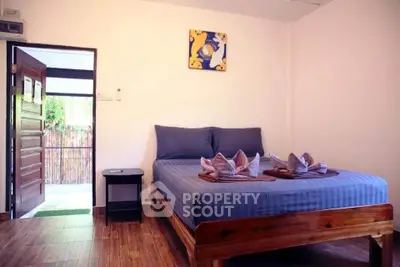 Cozy bedroom with wooden flooring and open door to balcony view.