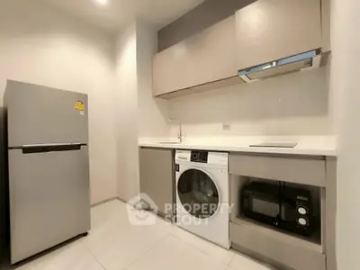 Modern kitchen with sleek appliances including fridge, washing machine, and microwave.