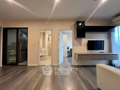 Modern living room with sleek flooring, wall-mounted TV, and open layout leading to kitchen and study.
