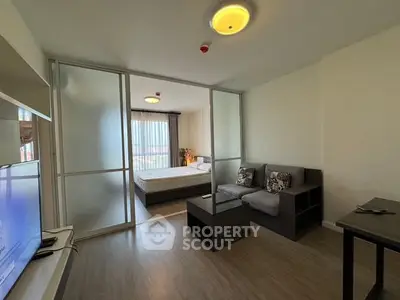 Modern living room with sliding glass doors leading to a cozy bedroom, featuring stylish furniture and natural light.