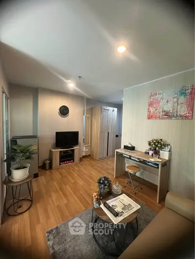 Modern living room with stylish decor and wooden flooring, featuring a cozy seating area and a compact workspace.