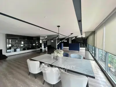 Spacious modern living room with elegant dining area and large windows offering natural light.