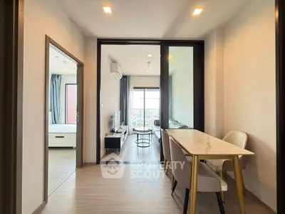 Modern apartment interior with open living and dining area, featuring sleek furniture and natural light.