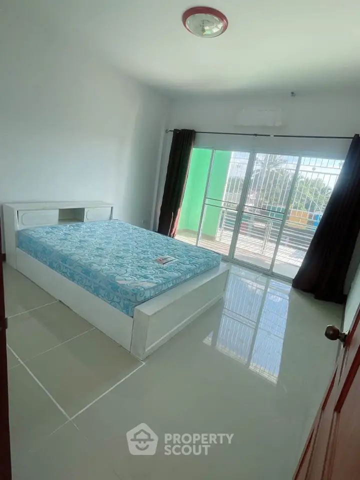 Spacious bedroom with large window and balcony access, featuring a modern bed and glossy tiled floor.
