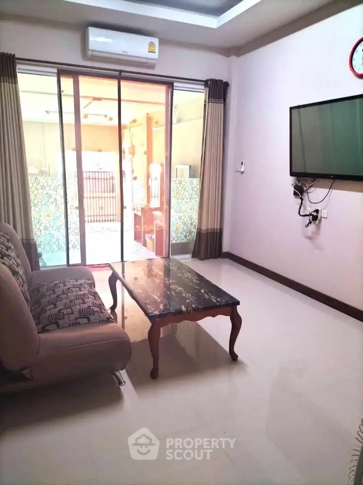 Modern living room with sleek furniture and large sliding glass doors leading to a balcony.