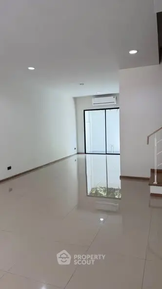 Spacious modern living room with glossy tiled floors and large windows for natural light.