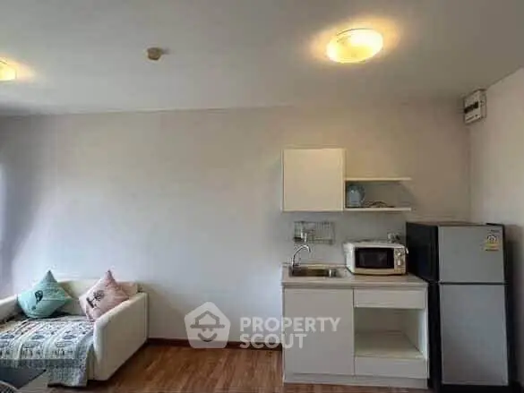 Cozy studio apartment with compact kitchen and comfortable seating area, perfect for urban living.