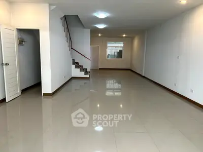 Spacious open-plan living area with sleek tile flooring and modern staircase.