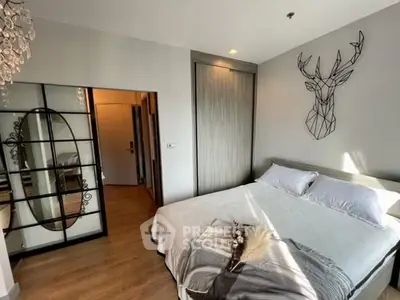 Modern bedroom with stylish decor and natural light, featuring a unique wall art and cozy bedding.