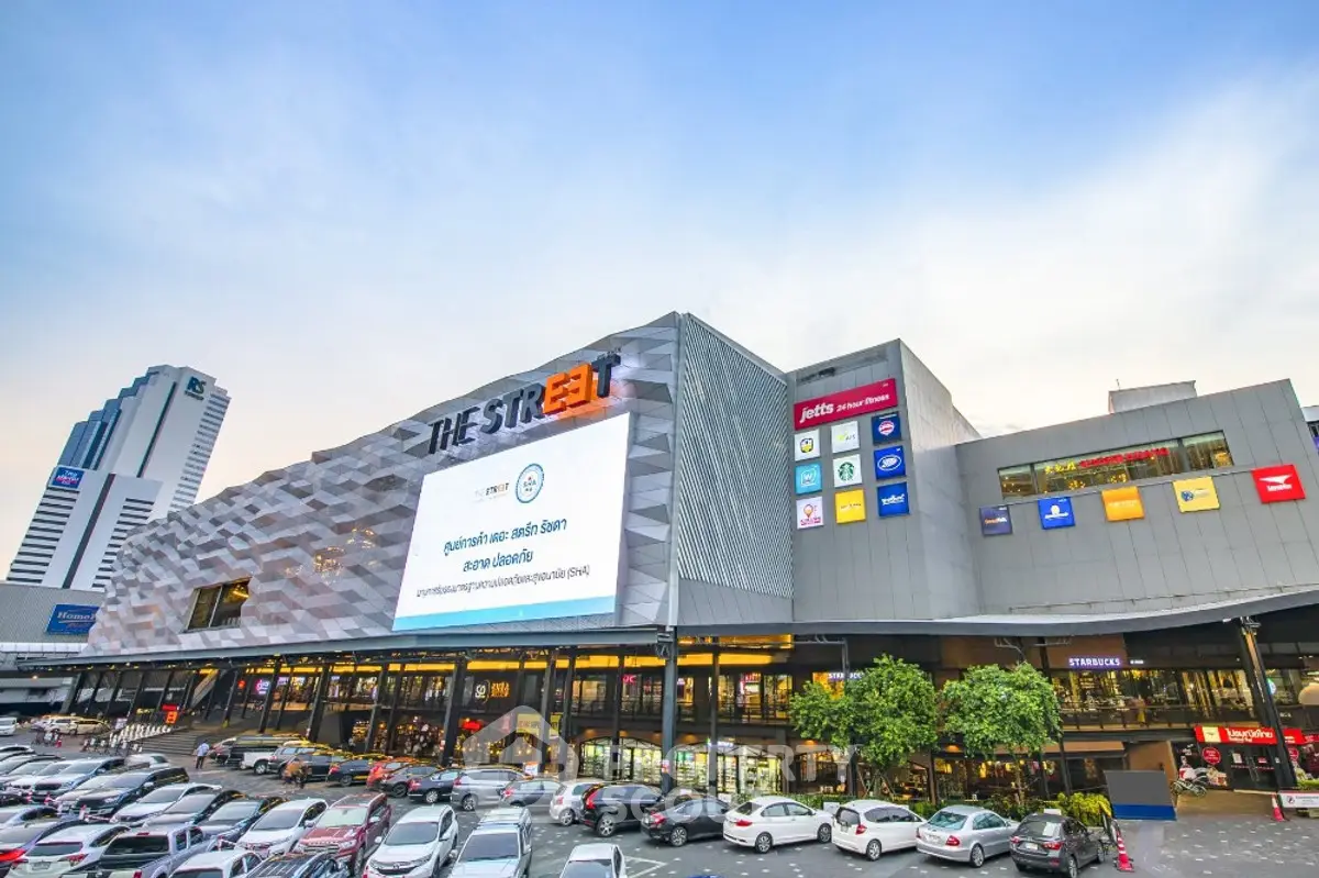 Modern shopping mall exterior with vibrant signage and ample parking space.