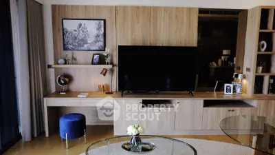 Modern living room with wooden paneling and large TV, featuring stylish decor and glass table.