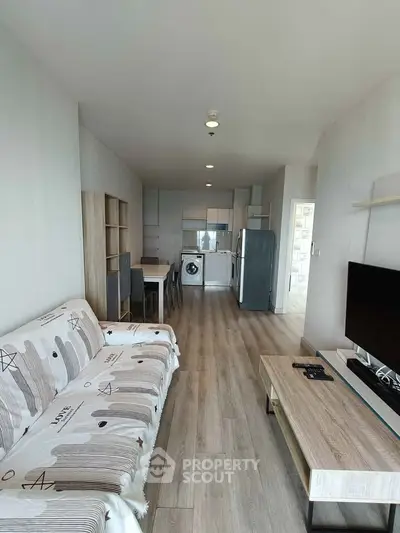 Modern living room with open kitchen, featuring stylish furniture and appliances, perfect for urban living.