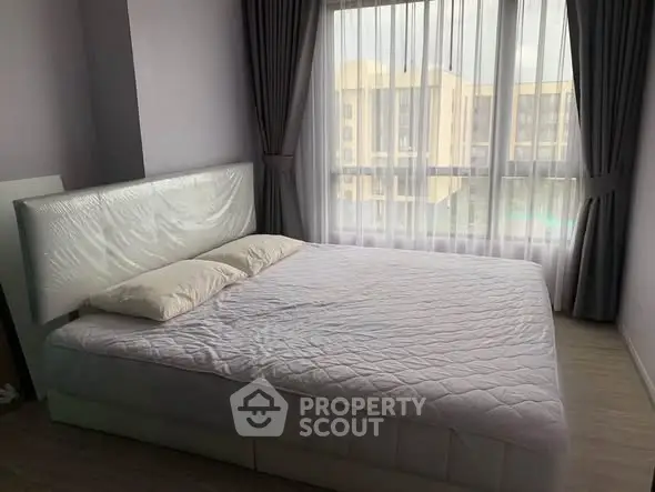 Spacious bedroom with large window and modern decor in a stylish apartment.