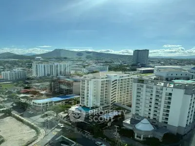 Stunning cityscape view from high-rise building with mountains in the background, perfect for urban living.