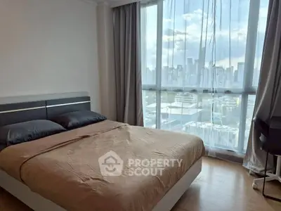 Modern bedroom with city view and natural light, featuring a comfortable bed and sleek design.
