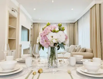 Elegant living room with stylish decor and dining setup, featuring a cozy sofa and large windows.