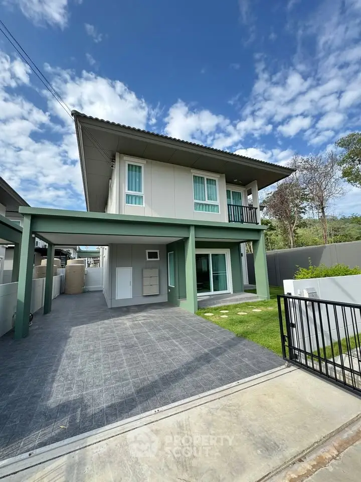 Modern two-story house with green accents and spacious driveway
