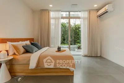 Modern bedroom with large windows and garden view, featuring stylish decor and air conditioning.
