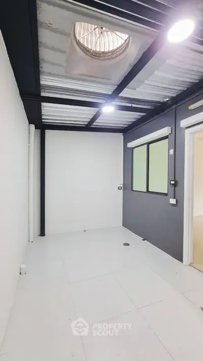 Modern minimalist room with industrial ceiling and large window, perfect for creative workspace.
