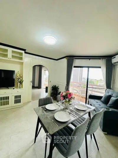 Elegant living room with dining area and city view, featuring modern decor and ample natural light.