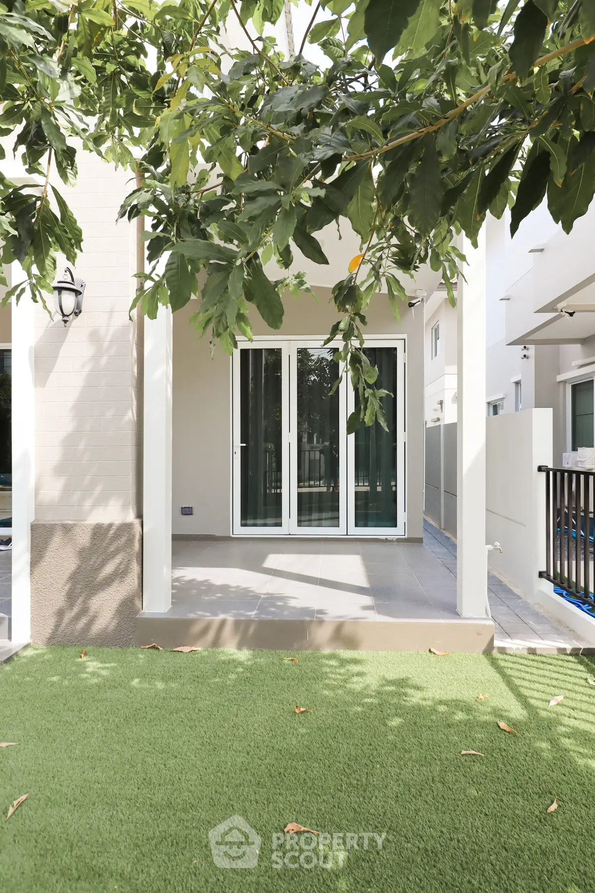 Charming modern home exterior with lush artificial grass and inviting patio area, perfect for outdoor relaxation.