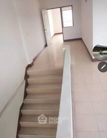 Spacious interior with tiled flooring and staircase leading to a bright room, ideal for modern living.
