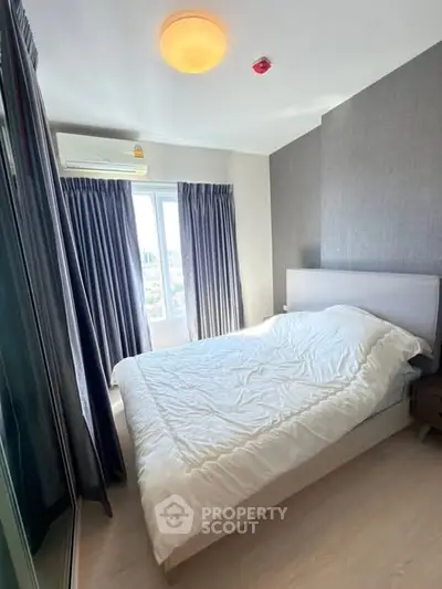 Cozy bedroom with modern decor and large window offering natural light.
