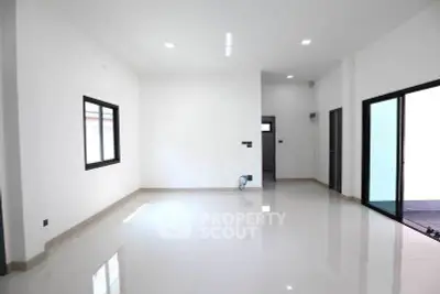 Spacious modern living room with large windows and sleek tile flooring.