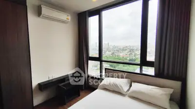 Modern bedroom with large windows offering stunning city views in a high-rise apartment.