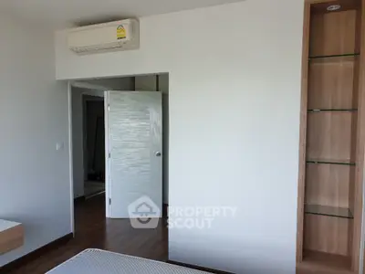 Spacious and well-lit bedroom with modern air conditioning unit and built-in wooden shelving, perfect for comfortable living.
