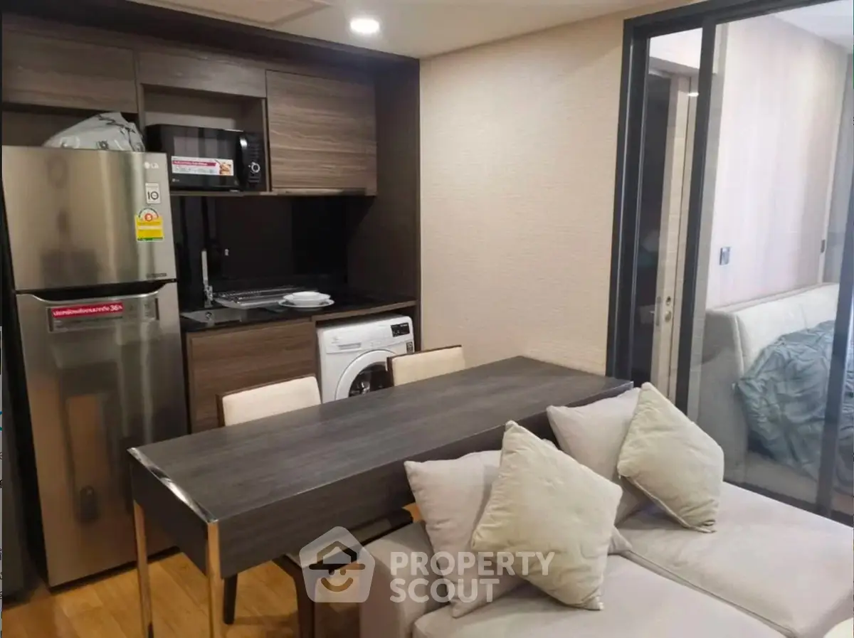 Modern apartment interior with kitchen and living area featuring sleek appliances and cozy seating.
