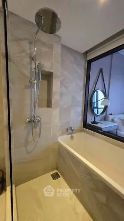 Modern bathroom with sleek shower and bathtub, featuring elegant tile design and large window.