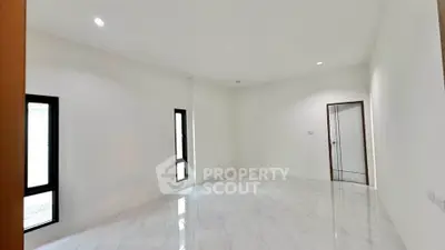 Spacious empty room with glossy white tiles and natural light from windows.