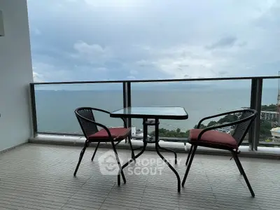 Stunning balcony with ocean view and cozy seating area, perfect for relaxation.