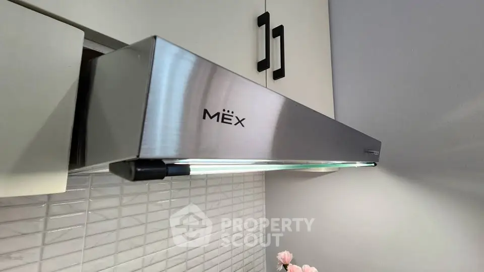Modern kitchen with sleek stainless steel range hood and stylish cabinetry.