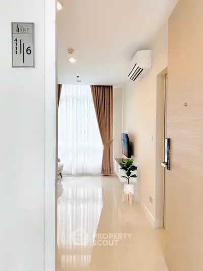 Modern apartment entrance with sleek flooring and natural light, featuring a cozy living area and stylish decor.