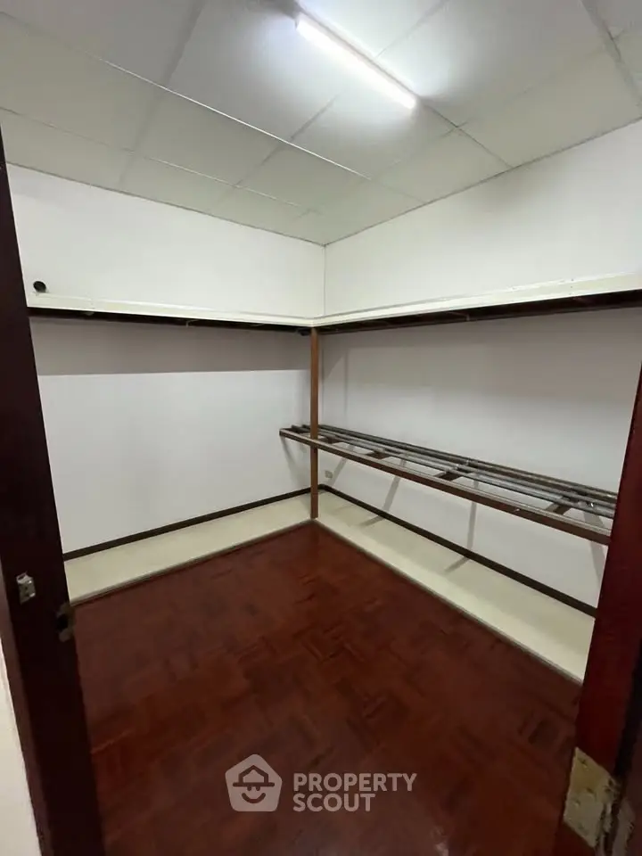 Spacious walk-in closet with wooden flooring and ample shelving space.