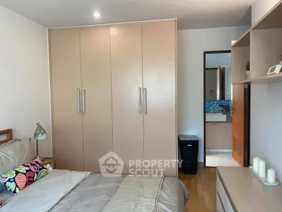 Cozy bedroom with built-in wardrobe and view into modern bathroom