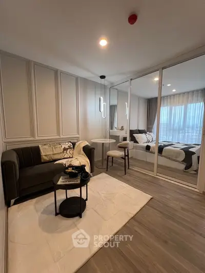 Modern studio apartment with stylish living area and cozy bedroom separated by glass partition.