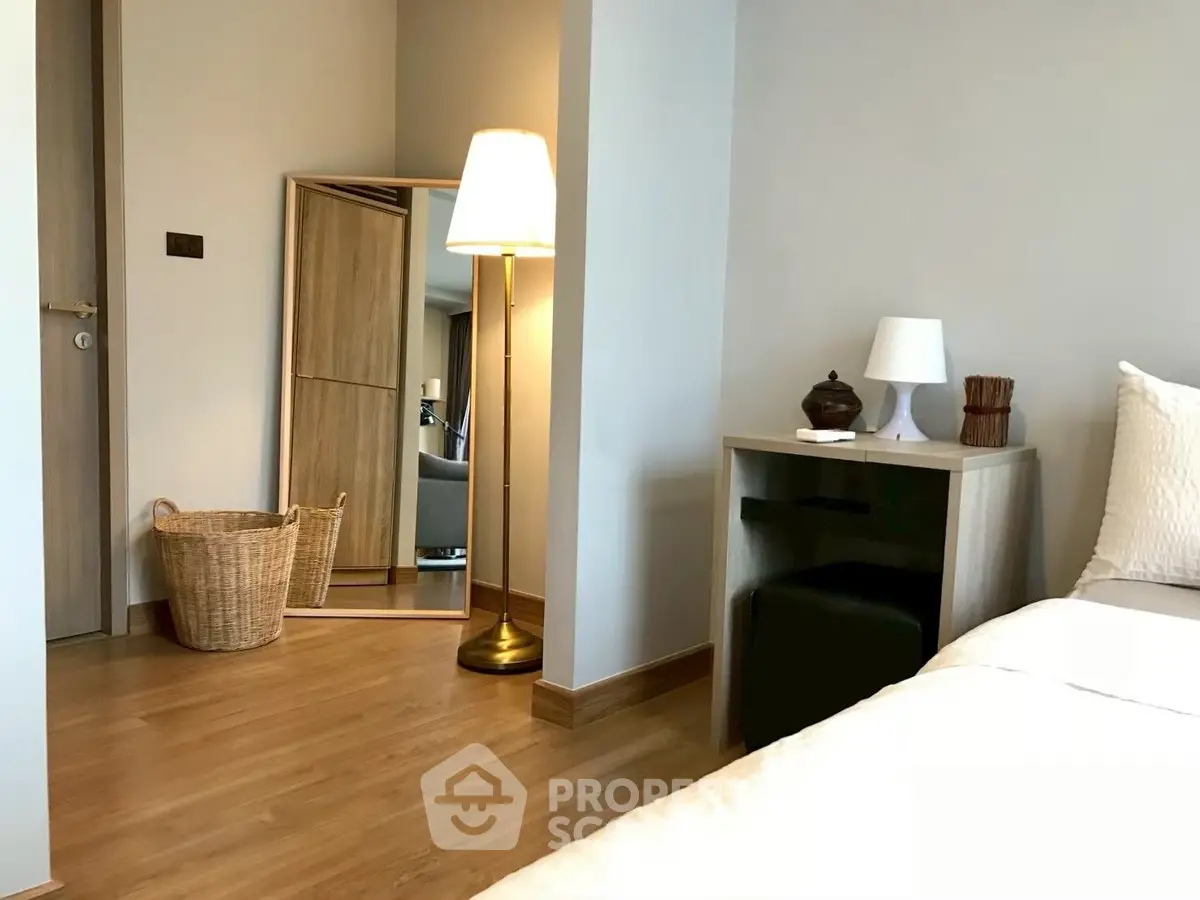 Cozy bedroom with modern decor, featuring a floor lamp, wicker basket, and stylish mirror.