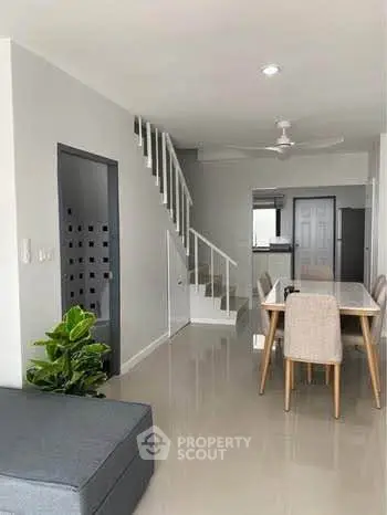 Modern living room with sleek staircase and dining area in stylish home