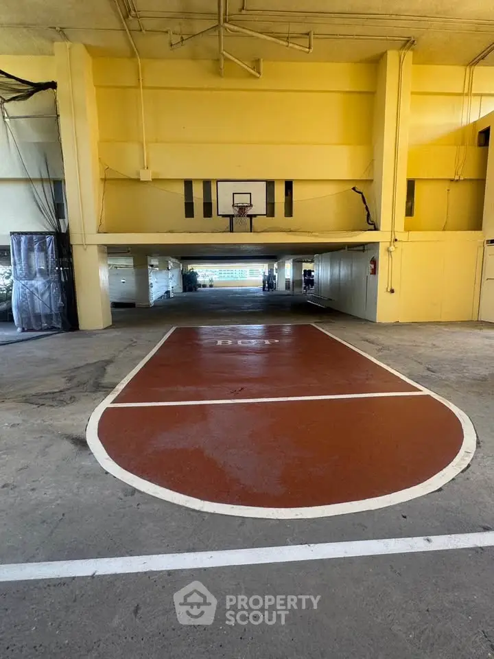 Spacious indoor basketball court in a residential building's parking area.