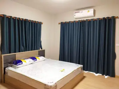 Spacious bedroom with modern air conditioning and elegant curtains, perfect for comfort and relaxation.