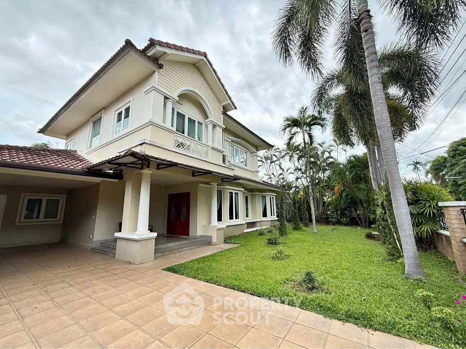 Elegant two-story house with lush garden and spacious driveway in tropical setting.