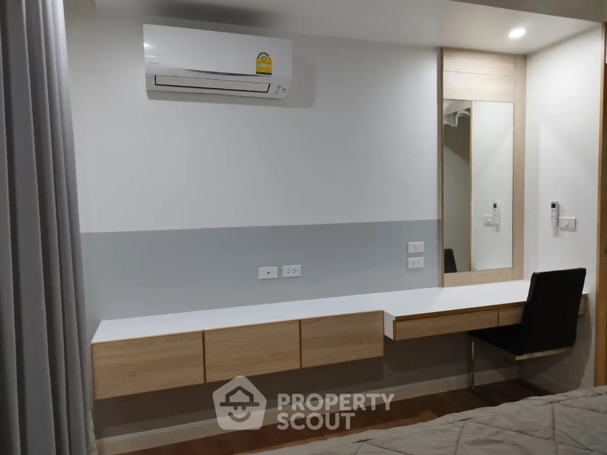 Modern bedroom with sleek desk, mirror, and air conditioning unit