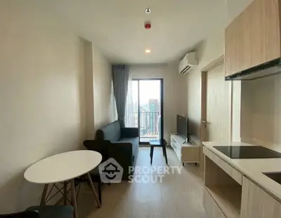 Modern living room with balcony view, sleek furniture, and open kitchen layout.