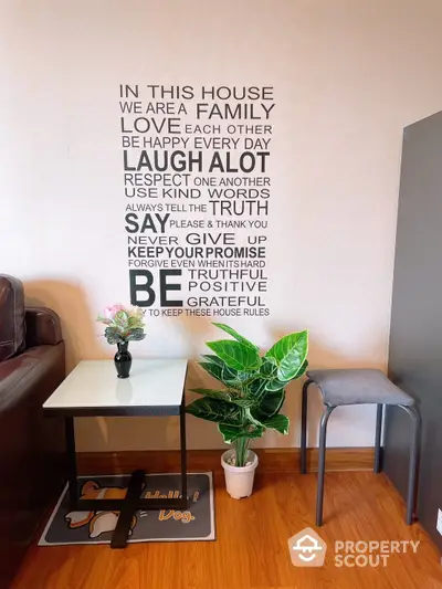 Cozy corner of a well-lit living room with inspirational wall art, a modern table, and vibrant houseplants adding a touch of greenery.