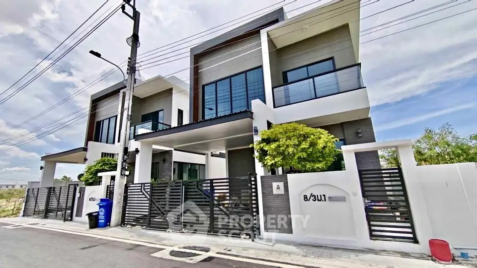 Modern two-story house with sleek design and spacious balcony in a suburban neighborhood.